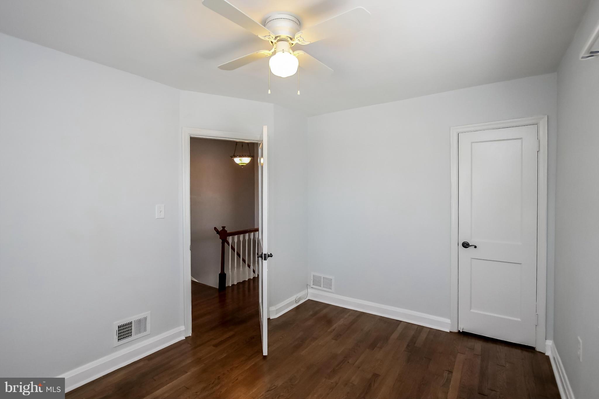 8329 Kavanagh Road Baltimore, MD 21222 - Photo 20 of 30 an empty room with wooden floor and a ceiling fan
