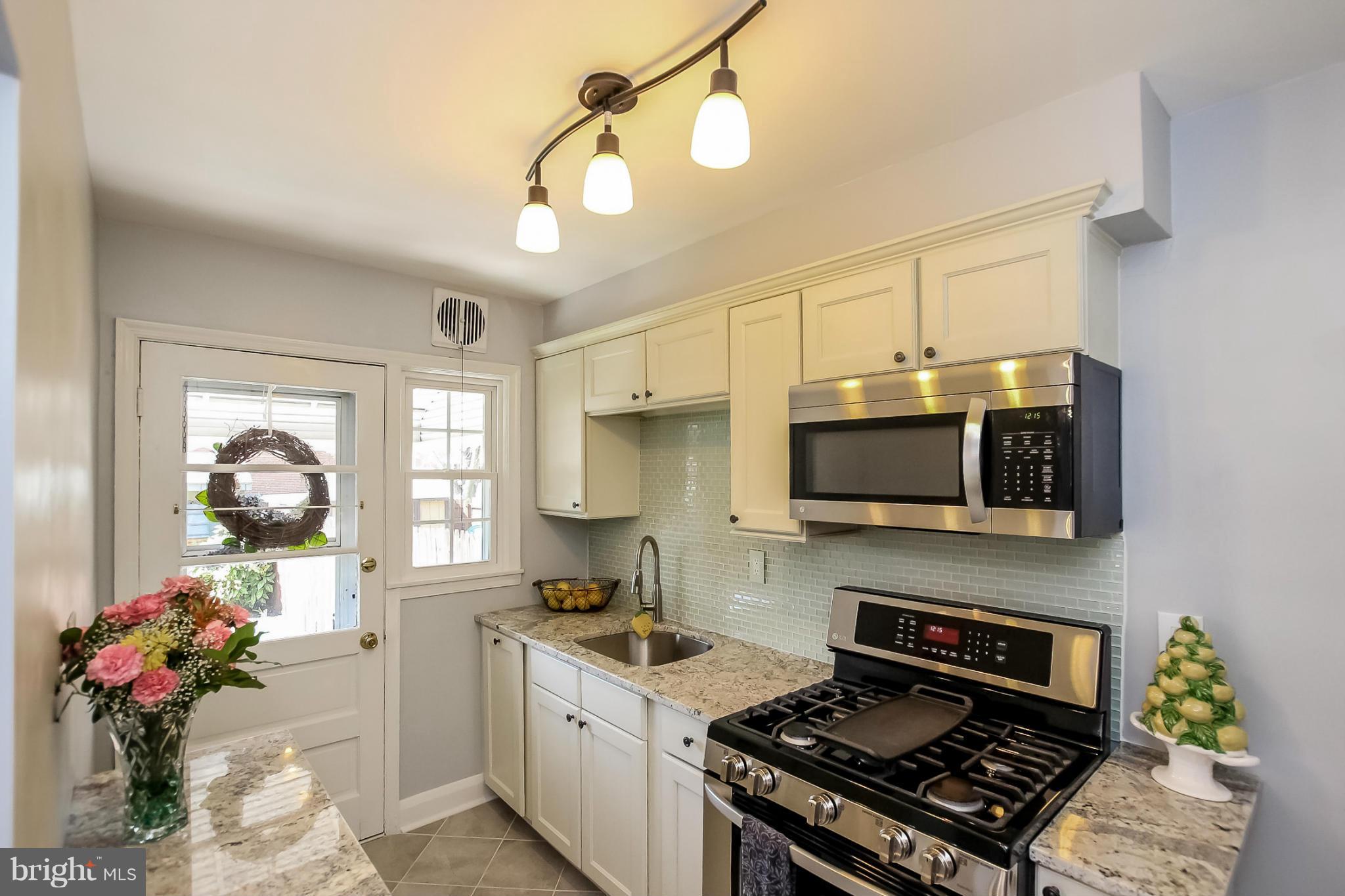 8329 Kavanagh Road Baltimore, MD 21222 - Photo 10 of 30 a kitchen with stainless steel appliances granite countertop a stove top oven a sink a counter space and cabinets