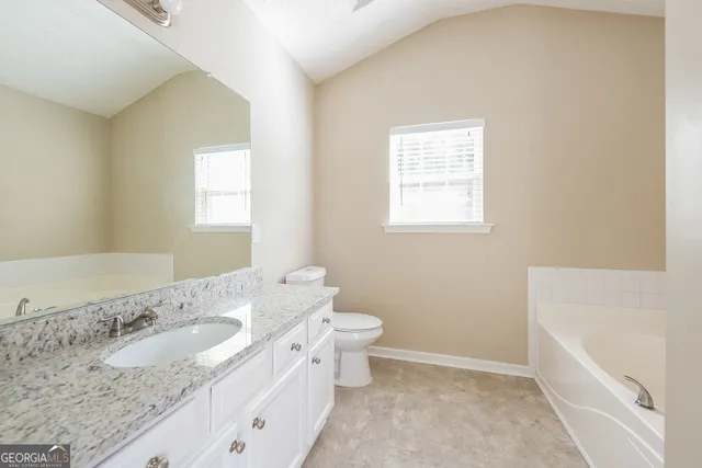 a bathroom with a granite countertop sink a toilet and bathtub