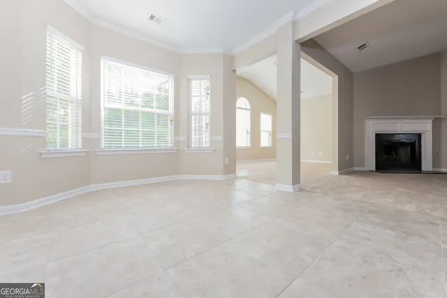 an empty room with windows and fireplace