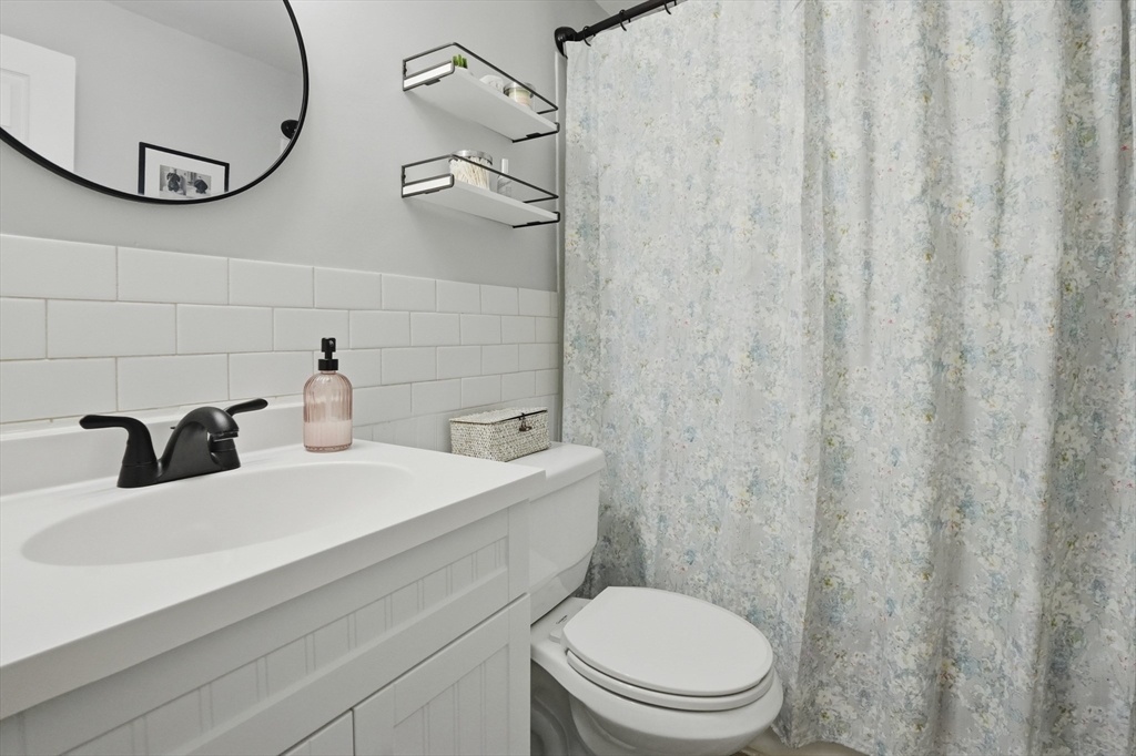 200 Manning Street, Unit 11C Hudson, MA 01749 - Photo 19 of 30 a bathroom with a sink a toilet and shower curtain