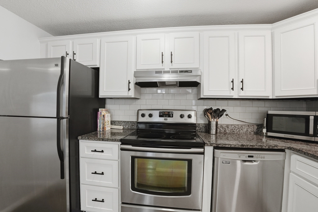 200 Manning Street, Unit 11C Hudson, MA 01749 - Photo 9 of 30 a kitchen with granite countertop white cabinets and stainless steel appliances