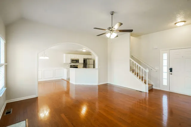 a view of empty room with wooden floor and fan