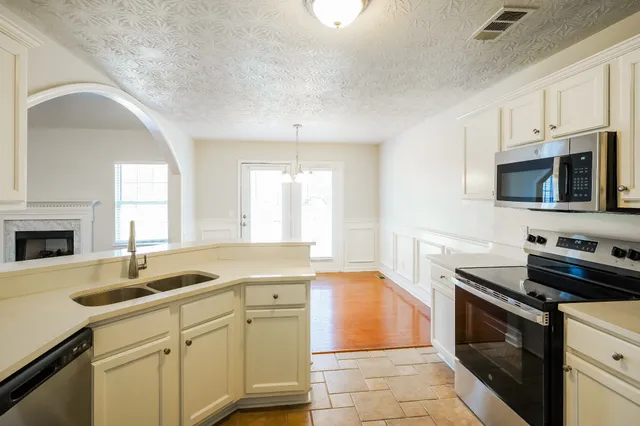 a kitchen with granite countertop a sink stainless steel appliances and white cabinets
