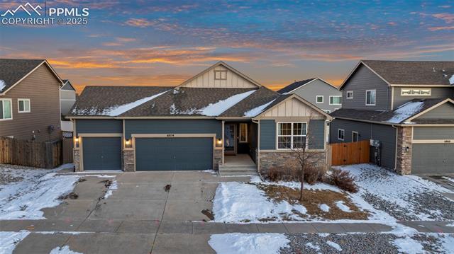 6854 Red Cardinal Loop Colorado Springs, CO 80908 - Photo 2 of 37 View of front of house featuring a three-car garage at dusk