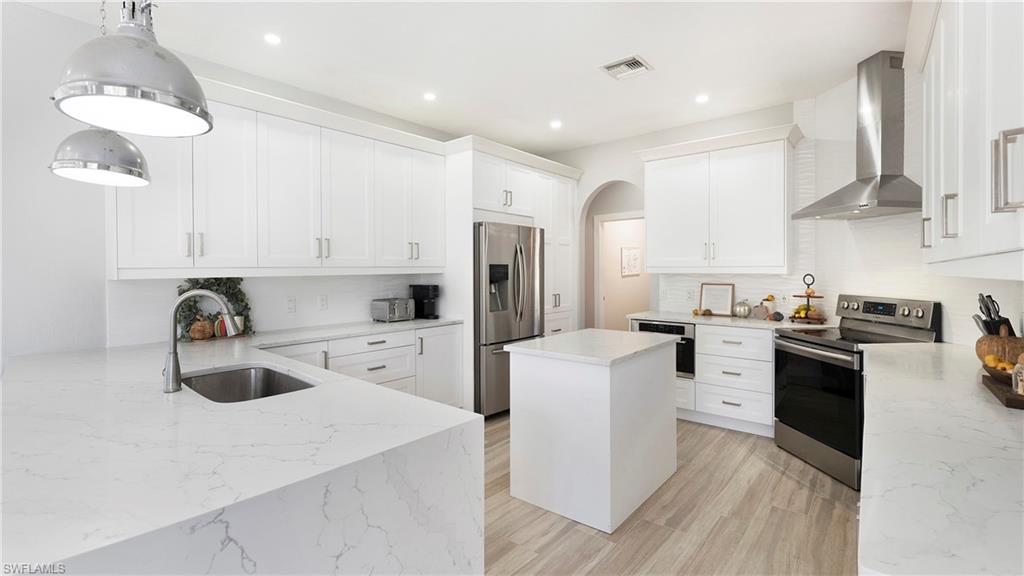 770 17th Street Southwest Naples, FL 34117 - Photo 12 of 47 a kitchen with white cabinets and stainless steel appliances