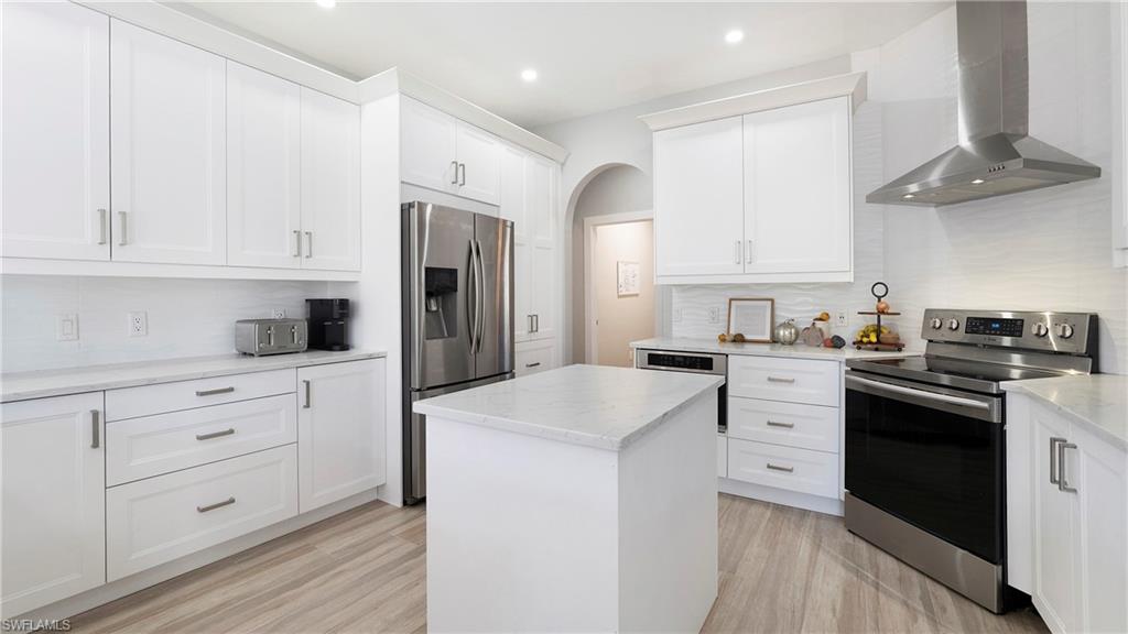 770 17th Street Southwest Naples, FL 34117 - Photo 14 of 47 a kitchen with stainless steel appliances granite countertop a sink dishwasher a refrigerator and white cabinets with wooden floor