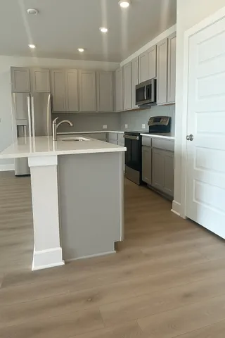 a view of kitchen with stainless steel appliances refrigerator a microwave and white cabinets