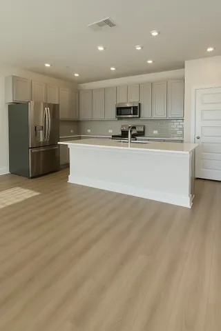 a large kitchen with stainless steel appliances a large counter top a stove and a sink