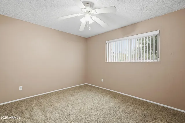 an empty room with windows and fan