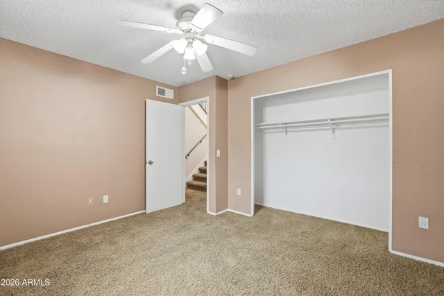 an empty room with a ceiling fan and carpet