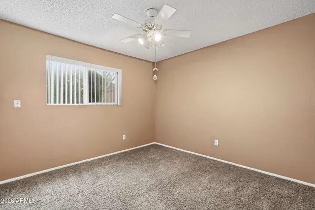 an empty room with windows and fan