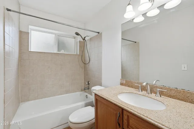 a bathroom with a granite countertop sink a toilet and shower