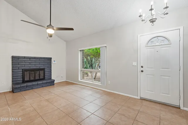 an empty room with windows fireplace and fan