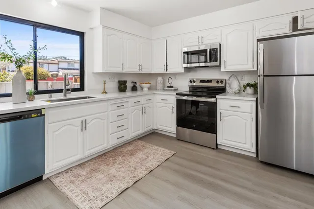 a kitchen with a refrigerator a stove top oven a sink and dishwasher with wooden floor