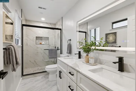 a bathroom with a double vanity sink toilet and shower