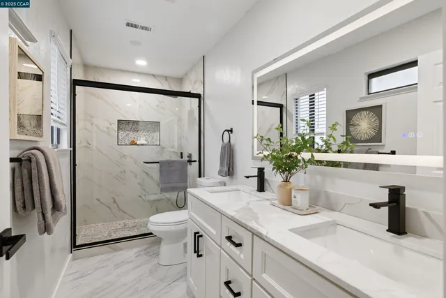a bathroom with a double vanity sink toilet and shower