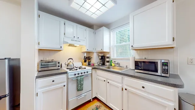a kitchen with stainless steel appliances granite countertop white cabinets a stove a sink and a white refrigerator