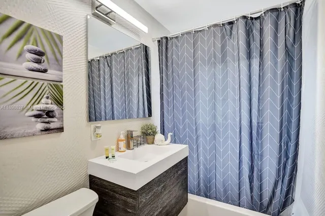 a bathroom with a sink a toilet and shower curtain