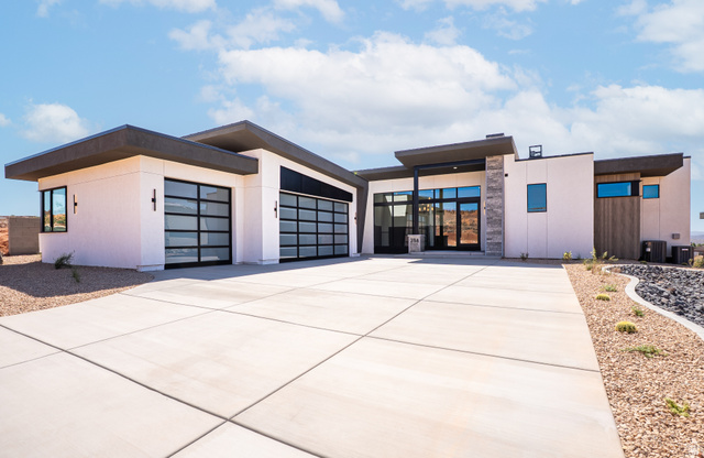 234 Colima Road, Unit 144 Washington, UT 84780 - Photo 1 of 21 Modern exterior with a flat roofline, stone cladding accents, large glass panel garage doors, and a concrete driveway