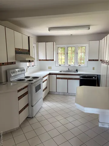 a kitchen with stainless steel appliances granite countertop white cabinets a sink and a stove