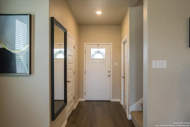 a view of a hallway with wooden floor and a bathroom