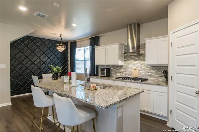a kitchen with granite countertop a sink cabinets and wooden floor