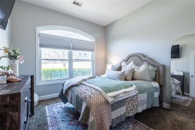 a bedroom with a bed and a flat tv screen on dresser