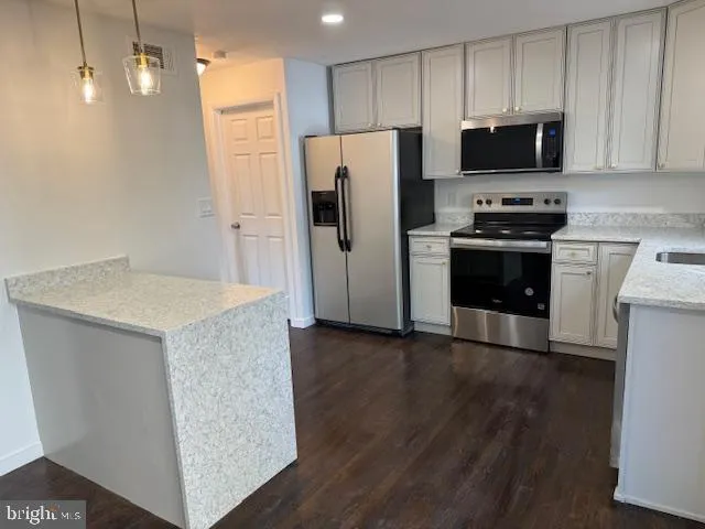 a kitchen with granite countertop a refrigerator and a stove top oven