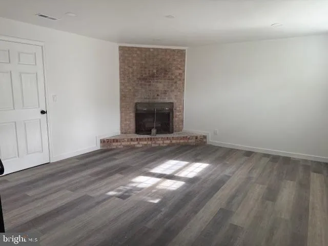 a view of empty room with wooden floor and fireplace