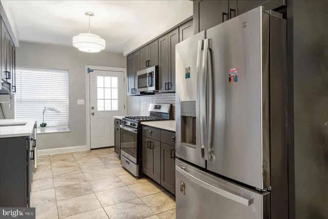a kitchen with granite countertop a refrigerator and a stove top oven