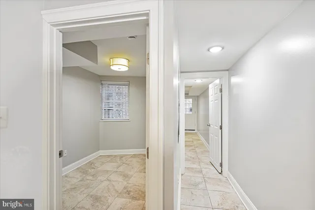 a view of a hallway with wooden floor and a bathroom