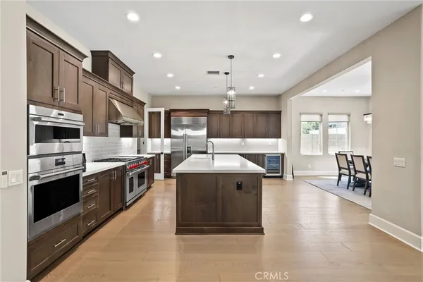 a large kitchen with stainless steel appliances granite countertop a large kitchen island a stove a sink a dining table and chairs
