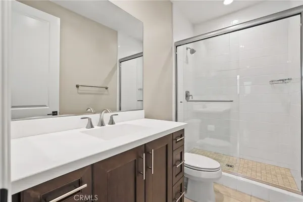 a bathroom with a sink a toilet a mirror and shower