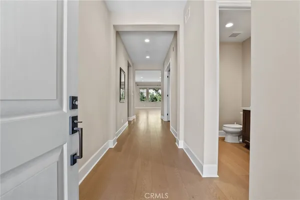 a view of a hallway with wooden floor and a bathroom