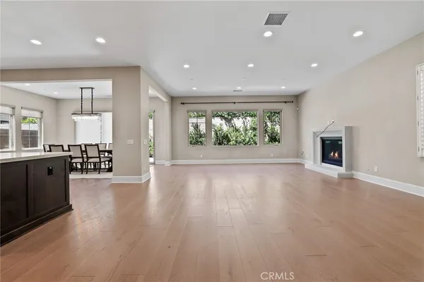 an empty room with wooden floor and a kitchen