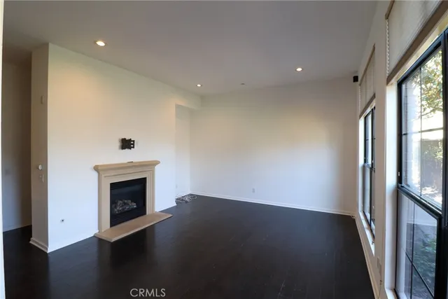 an empty room with wooden floor fireplace and windows