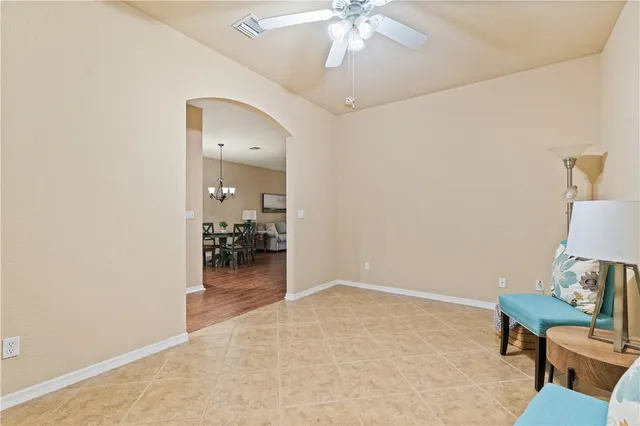a view of a livingroom with a dinning area hardwood floor and a chandelier fan