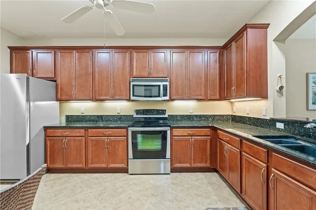 a kitchen with stainless steel appliances granite countertop wooden cabinets a stove a sink and a refrigerator