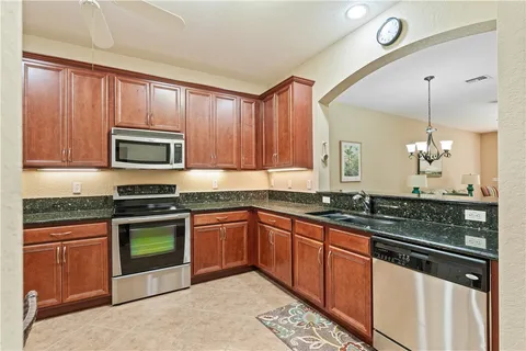 a kitchen with stainless steel appliances granite countertop wooden cabinets a stove a sink and a microwave