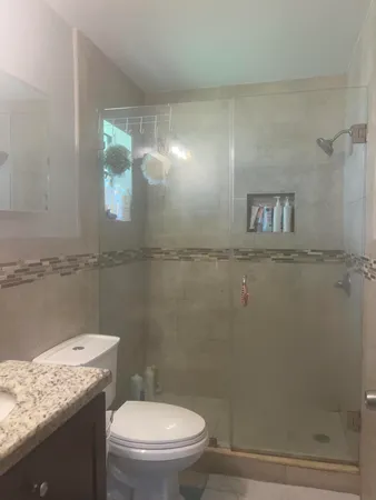 a bathroom with a granite countertop toilet and a sink