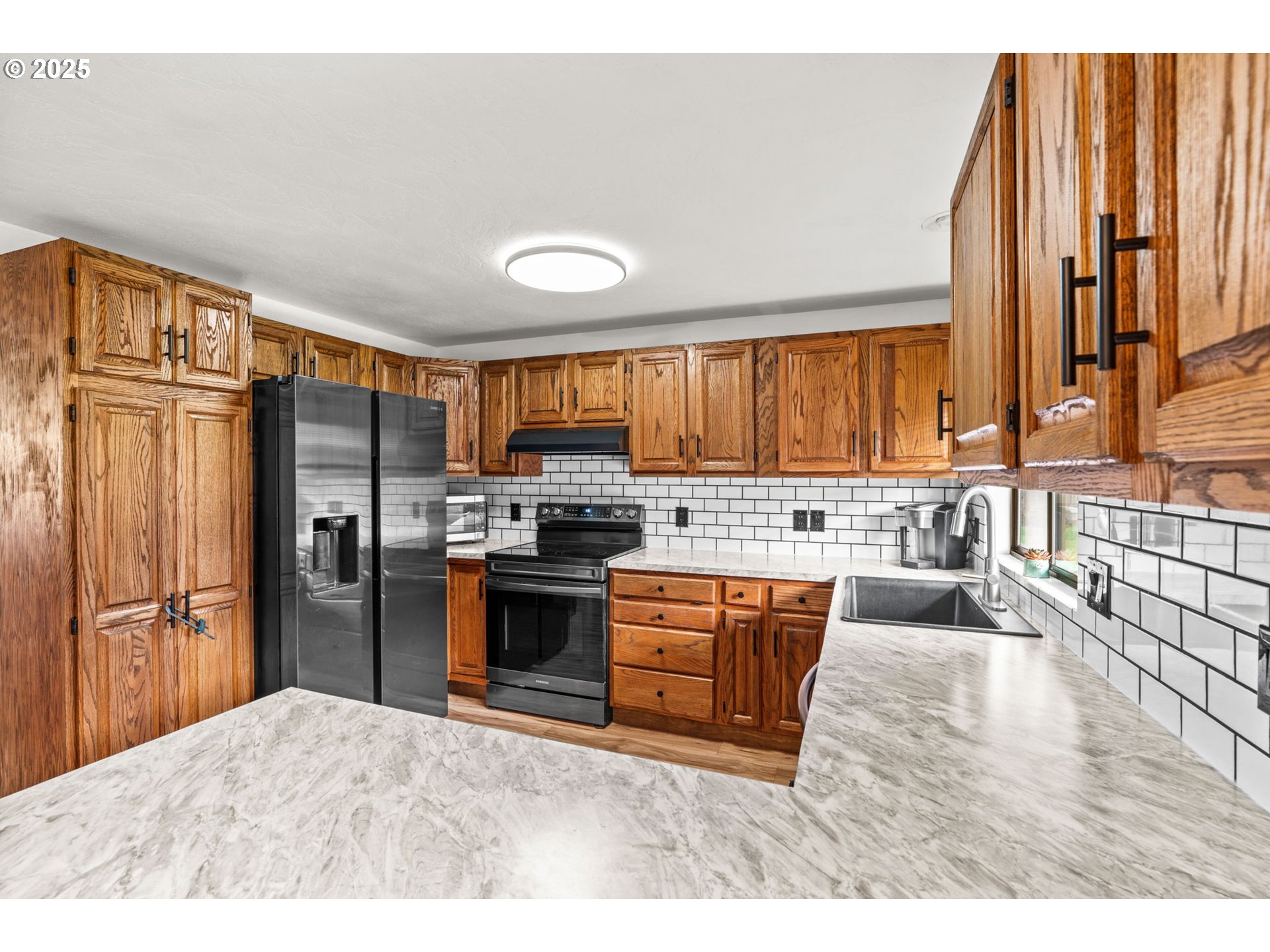289 73rd Place Springfield, OR 97478 - Photo 13 of 32 a kitchen with stainless steel appliances granite countertop a refrigerator a stove top oven and a sink with large window