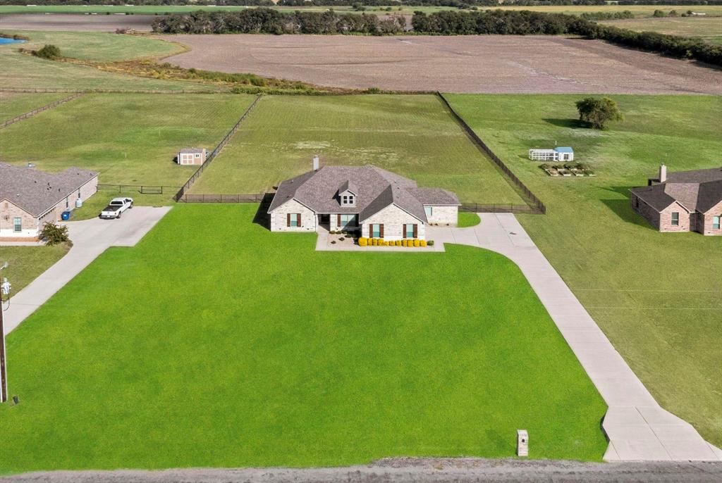 634 Gant Road Sherman, TX 75090 - Photo 6 of 40 Stone exterior residence featuring a gabled roof, a spacious green lawn, a concrete driveway, and a fenced backyard