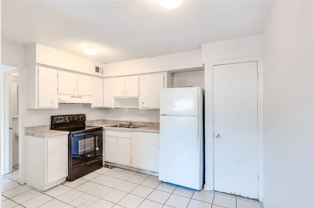 a kitchen with a refrigerator a stove top oven and cabinets