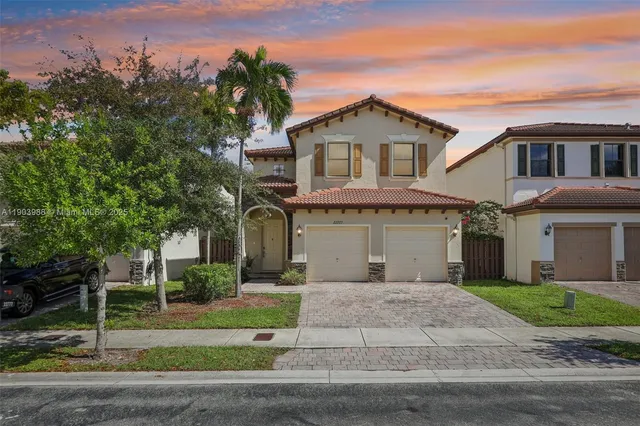 a front view of a house with a garden and trees