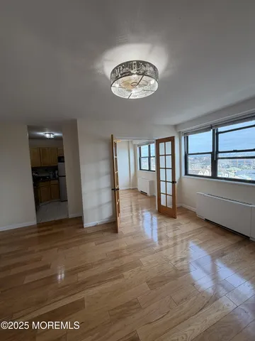 a view of an empty room with a window and wooden floor