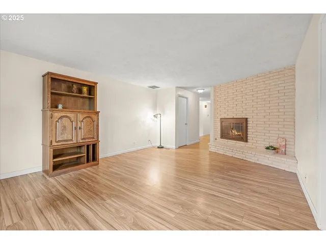 a view of empty room with a fireplace and wooden floor