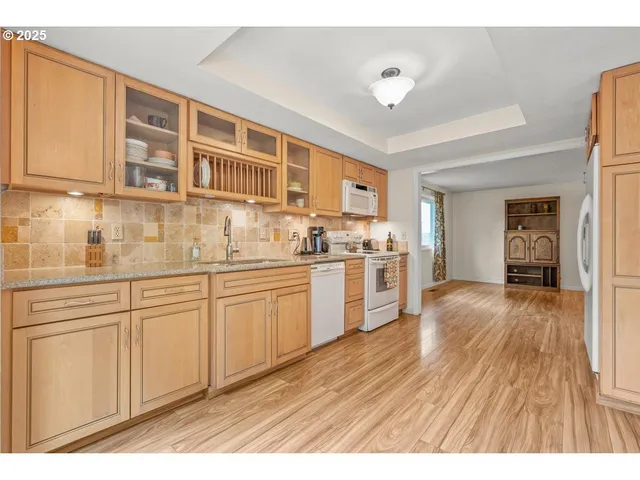 a kitchen with stainless steel appliances granite countertop a refrigerator a sink dishwasher and white cabinets with wooden floor