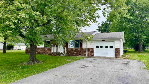 a front view of a house with a yard and trees