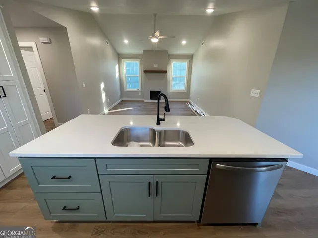 a kitchen with kitchen island stainless steel appliances a sink and wooden floor